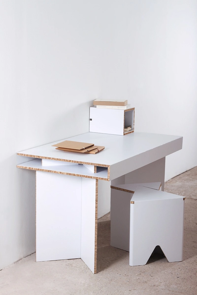 Mesa, estanterías y taburetes de cartón en local de estilo industrial